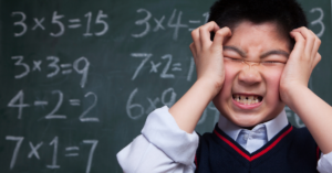 stressed schoolboy doing math at blackboard